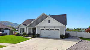 View of front of property featuring board and batten siding, a garage, a gate, a mountain view, and driveway