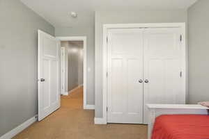 Bedroom with light carpet, baseboards, and a closet