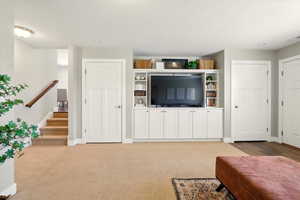 Living room with baseboards, light carpet, and stairway