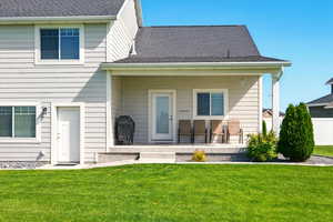 Rear view of property with a yard and a shingled roof