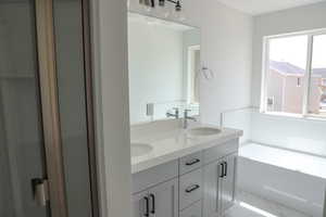 Full bathroom with double vanity, marble finish flooring, and a bath