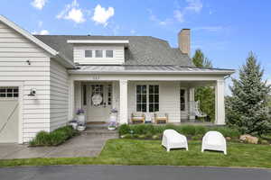 View of front of home with a standing seam roof, a porch, roof with shingles, and metal roof