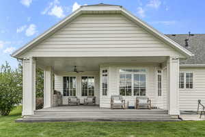 Back of property featuring a ceiling fan, a lawn, a shingled roof, a deck, and an outdoor hangout area