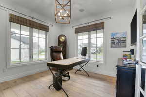 Office area with crown molding, healthy amount of natural light, a chandelier, baseboards, and light wood finished floors
