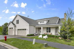 View of front of home with a standing seam roof, concrete driveway, a porch, a front lawn, and roof with shingles