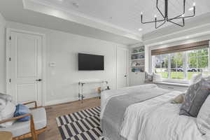 Bedroom featuring wood finished floors, baseboards, a chandelier, recessed lighting, and a raised ceiling