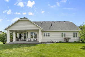 Rear view of property featuring a ceiling fan, outdoor lounge area, a yard, a shingled roof, and a patio