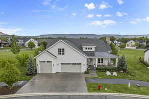 Modern inspired farmhouse featuring a porch, a mountain view, a front yard, and driveway