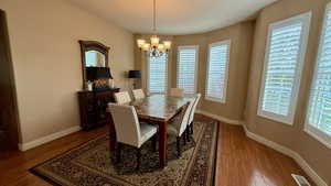 Dining space featuring wood finished floors, a chandelier, and baseboards