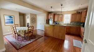 Kitchen with oven, a kitchen island, wood finished floors, decorative backsplash, and baseboards