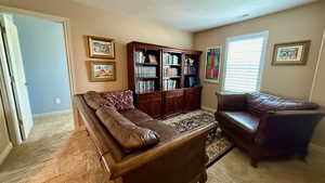 Living area featuring light colored carpet, a textured ceiling, and baseboards