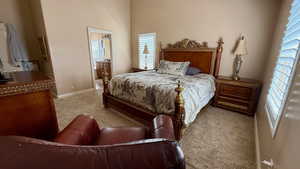 Carpeted bedroom featuring baseboards and a towering ceiling