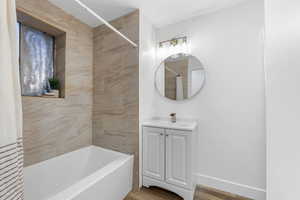 Full bathroom with vanity, shower / tub combo with curtain, wood finished floors, baseboards, and a textured ceiling