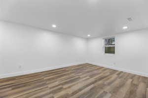 Unfurnished room with wood finished floors, baseboards, and recessed lighting