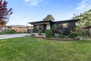 View of front of property with concrete driveway, brick siding, a front lawn, and a porch