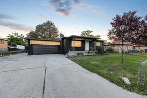 View of front of property with concrete driveway, brick siding, a garage, and a porch