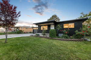 View of front facade featuring driveway, a lawn, brick siding, and covered porch