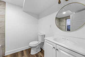 Bathroom with vanity, wood finished floors, baseboards, and toilet