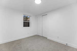Unfurnished bedroom with light carpet, baseboards, and a closet