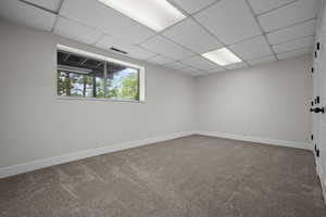 Unfurnished room featuring carpet flooring, baseboards, and a paneled ceiling