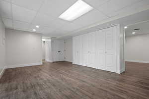 Below grade area with dark wood-type flooring, baseboards, recessed lighting, and a drop ceiling
