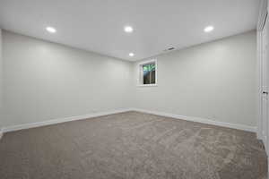 Carpeted empty room featuring recessed lighting and baseboards