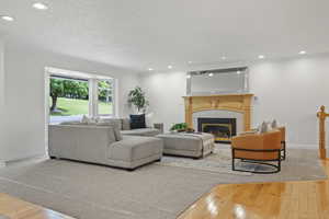 Living area with hardwood / wood-style flooring, crown molding, a tile fireplace, baseboards, and recessed lighting
