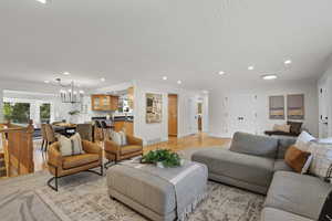 Living area with recessed lighting, a chandelier, crown molding, a textured ceiling, and light wood-type flooring