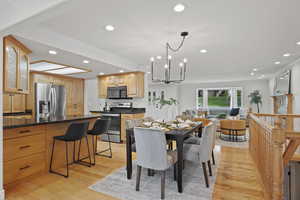 Dining area featuring crown molding, light wood-style flooring, recessed lighting, and a chandelier