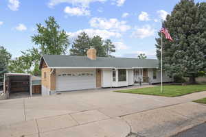 Ranch-style home featuring an attached garage, a shingled roof, a front lawn, a chimney, and concrete driveway