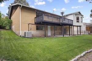Rear view of house with a deck, a yard, central AC unit, and a patio