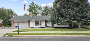 Single story home featuring concrete driveway, a garage, a chimney, a front yard, and roof with shingles