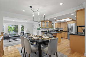 Dining room featuring light wood-style flooring, crown molding, recessed lighting, and a chandelier