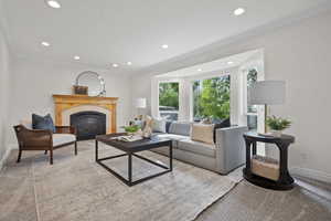 Living area with baseboards, carpet flooring, a glass covered fireplace, recessed lighting, and ornamental molding