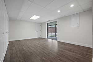 Spare room with dark wood-style floors, a drop ceiling, and baseboards