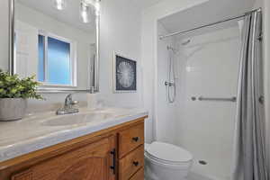 Bathroom with toilet, vanity, and tiled shower