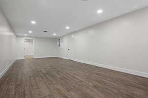 Finished below grade area featuring recessed lighting, dark wood-style floors, and baseboards