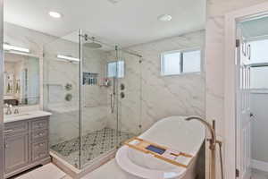 Bathroom with a freestanding tub, a marble finish shower, vanity, and recessed lighting