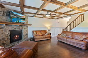 Living room with wood finished floors, a fireplace, beamed ceiling, coffered ceiling, and ceiling fan