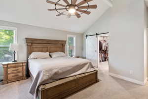 Bedroom featuring light carpet, a barn door, baseboards, a spacious closet, and ceiling fan
