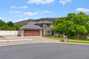 Traditional-style house with stone siding, a mountain view, a gate, and an attached garage