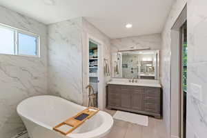 Full bathroom with tile walls, vanity, a soaking tub, a marble finish shower, and recessed lighting