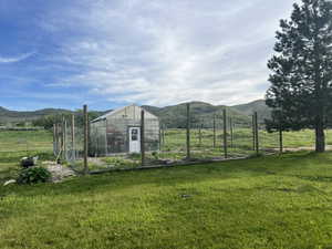 View of greenhouse with a mountain view, a yard, and a garden