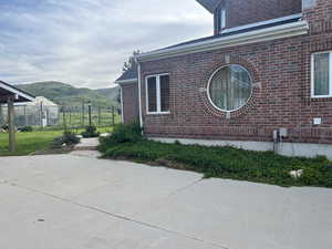 View of side of home featuring a mountain view, brick siding, and a patio