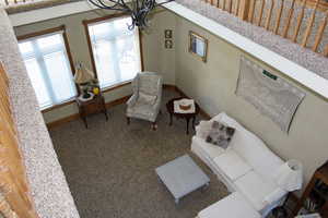 Living area featuring a chandelier, baseboards, and carpet floors