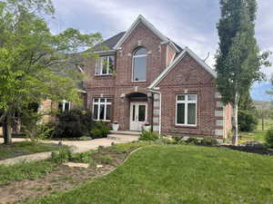 Traditional-style house with brick siding and a front lawn