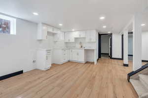 Kitchen featuring a sink, light wood-style flooring, white cabinets, light countertops, and recessed lighting