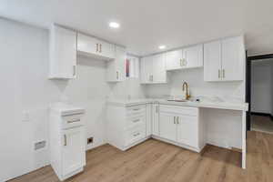 Kitchen featuring a sink, light wood finished floors, white cabinets, and recessed lighting