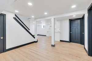Below grade area featuring baseboards, light wood finished floors, stairway, and recessed lighting