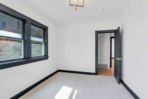 Carpeted spare room with a smoke detector and baseboards